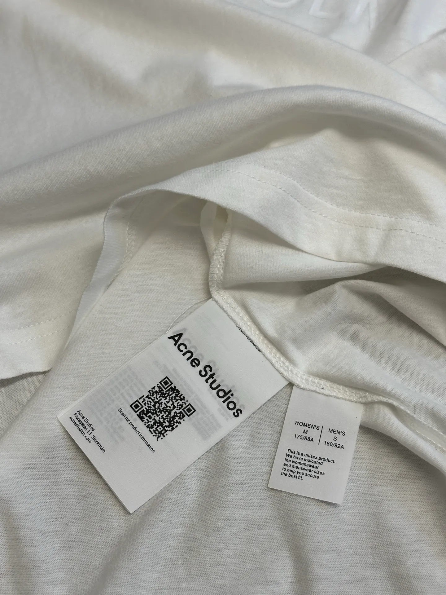 Ac Original White Letter Round Neck Long Sleeve The fabric is made of 32-count cotton and linen blended plain knitting, with a ratio of 85% cotton and 15% linen fiber. The weight is only 145g/m²; the ribbed neckline is made of Same Style cotton and linen blended yarn, 145g/m², to ensure a unified texture of the entire piece. The collision of the natural rough base and the industrial spraying process creates a natural irregular texture and an extremely light and breathable wearing experience. Cotton provides a skin-friendly and soft foundation, while linen introduces natural roughness and knotted particles, giving the fabric surface an irregular texture. The addition of hemp fiber makes the fabric have excellent moisture absorption and perspiration properties, while also bringing a natural micro-wrinkle texture and dry touch. After the fabric is piece-dyed, the dye evenly penetrates into the fiber, showing full color fastness and soft matte color, providing a uniform base for subsequent inkjet printing. The printing uses a double-layer printing process of environmentally friendly elastic glue and varnish, which takes into account the concept of environmental protection, wearing comfort and visual expression. The bottom layer uses environmentally friendly elastic glue, with water-based environmentally friendly resin as the base material. The color paste is scraped onto the surface of the fabric through a high-mesh screen. After drying and solidifying at high temperature, a soft and highly elastic continuous adhesive film is formed. The printed film can stretch and retract with the fabric. Even if it is covered with a large area of ​​pattern, it is still breathable and does not feel tight when wearing it. The surface layer is accurately overprinted with transparent varnish, creating a high-gloss effect in specific areas. This layer of varnish not only significantly improves the color contrast of the pattern, but also creates a local wet and bright visual and tactile contrast, making ordinary printing instantly gain three-dimensional layers and glossy texture. At the same time, the smooth surface layer also enhances Wear-Resistant and wash-resistant properties. This T-shirt is defined as a casual loose cut, unisex style, and hip length. The light fabric slides smoothly along the body contours, forming natural and soft folds at the shoulders and waist. The shoulder line falls naturally, the bust and hem circumferences are similar, and it presents a straight silhouette, without deliberately distinguishing between male and female body shapes. The hip-length design utilizes the elongated body and the extremely light drape of the fabric to create lazy and flowing lines. The ribbed neckline, cuffs and hem are all made of Same Style cotton and linen blended yarn, which maintains a unified overall texture and is loose yet exquisite in details. size：xs s m l